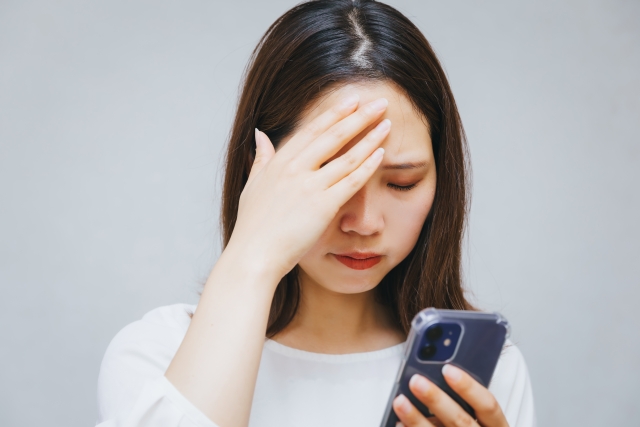 スマホを持って悩む女性
